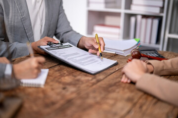 A woman is writing on a contract in front of two other people