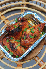 Homemade baked chicken breast in the aluminum foil box served on the table barbeque grill....