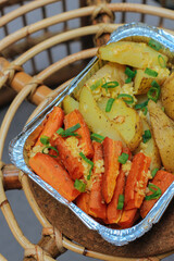 Healthy vegetarian barbecue with fresh vegetable grilling over the coals including carrots and potato, in foil for baking on an oven tray. Cooking in the oven. Selective focus