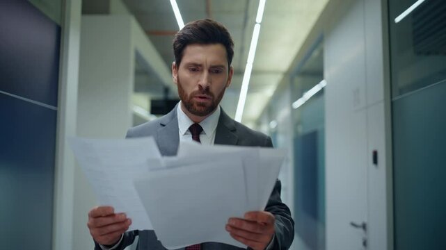 Tensed director reading report stepping corridor closeup. Nervous business owner