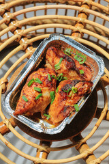 Homemade baked chicken breast in the aluminum foil box served on the table barbeque grill. Selective focus. 
