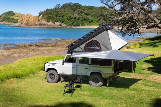 Land Rover Defender 110 (2012), with custom Alu-Cab Icarus pop-top camper conversion, freedom camping at a beautiful secluded New Zealand beach. Near Whananaki, Whangārei district, Northland Region.