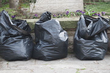 Trash bags collected in garden area near floral decoration