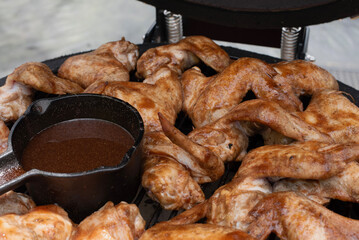 Barbecue chicken wings grilling with sauce on an outdoor grill.
