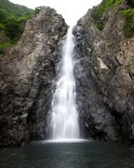 Cascading Waterfall Amidst Rugged Cliffs and Verdant Foliage in a Tranquil Natural Setting