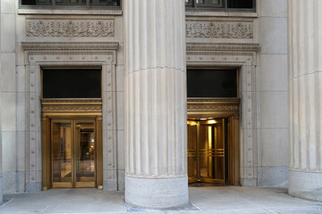 Entrance to office building with large stone columns and brass revolving doors