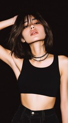 Young woman in black crop top and high-waisted pants with layered silver necklace