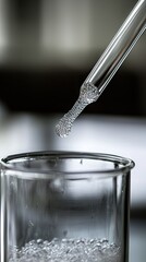 Dropper adding liquid to beaker; lab research