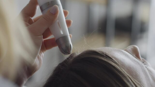 Cosmetologist performing hydrafacial vacuum cleansing on young womans face.