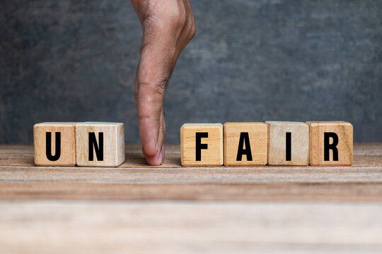 male hand put away first two letter from unfair word to be read fair isolated on yellow background. fairness concept