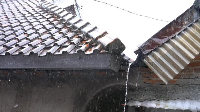 Heavy rainstorms made water flow from the roof tiles of the house