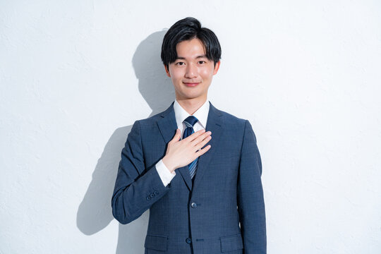 胸に手を当てるスーツを着た男性