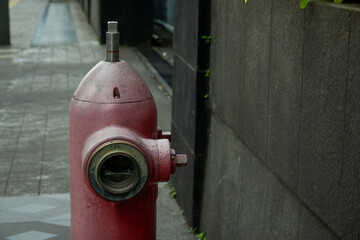 a worn out fire hydrant in Jakarta City, Indonesia, with faded red color, placed in a sidewalk
