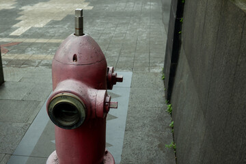 a worn out fire hydrant in Jakarta City, Indonesia, with faded red color, placed in a sidewalk