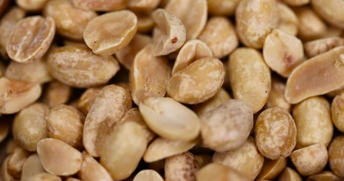 fried peeled peanut kernels in a wooden bowl, fried yellow peanuts with a little salt on the table, close up