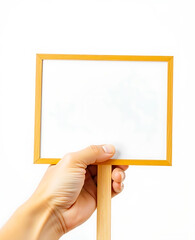 The image shows a hand holding a small clear wooden sign with a blank white surface ideal for adding text or graphics. Protester hand holding blank placard sign on wooden stick. Empty Message Board.