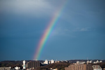 丘の上の住宅群に架かる虹の端