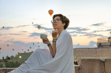 Young woman looking at hot air balloons and beautiful morning landscape of Goreme, travel vacation in Cappadocia, Turkey