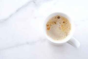 淹れたてのコーヒー（カフェラテ）が入ったマグカップを、真上から俯瞰した画像
