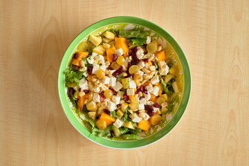 Fresh fruit and cheese salad with nuts in a green bowl