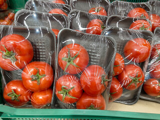 Tomatoes in plastic bags on the shelf in the grocery store.