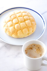 おいしそうなメロンパンと、淹れたてのコーヒー（カフェラテ）で、おやつの時間	
