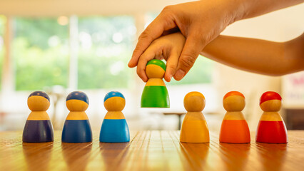Generated ImageFather holds son's hand to pick up a green human model from a group. Concept of teaching children to choose friends and divide tasks appropriately according to their responsibilities.