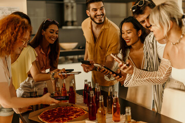 Friends taking photos of pizza and drinks with smartphones at a party