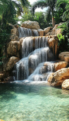 Naklejka premium tropical waterfall cascading into natural pool, surrounded by lush greenery and rocks, creates serene and tranquil atmosphere, inviting relaxation and peace