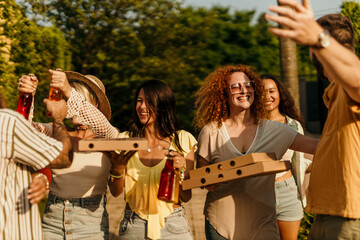 Cheerful people carrying pizza and drinks laughing together at a party