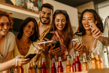 Group of diverse friends taking photos of pizza and drinks with smartphones at a party
