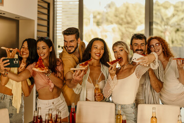 Group of diverse cheerful friends taking selfie while eating pizza at a party