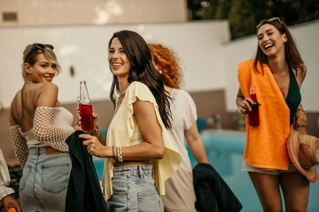 A happy women holding drinks and smiling at a rooftop party