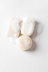 Set of different soap bars with foam on white background, top view