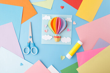 Handmade greeting card with 3D paper hot air balloon, clouds, and heart shapes on a blue...