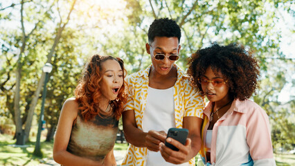 Friends, phone and surprise with social media at park for online update, gossip post and drama news. Gen z people, shocked and smartphone with internet information, announcement or text notification