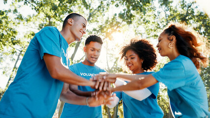 Volunteer, team or people stack hands for support, donation goal or cooperation in low angle outdoor. Huddle together, community service or group at charity NGO, smile or motivation for collaboration