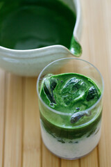 Matcha latte, Cup of fresh matcha tea, green tea with milk and whipped cream on wooden table.