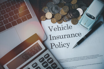 selective focus image of document car insurance policy toys car computer laptop calculator  writing pen and coins on table in concept of vehicle insurance risk management and financial planning