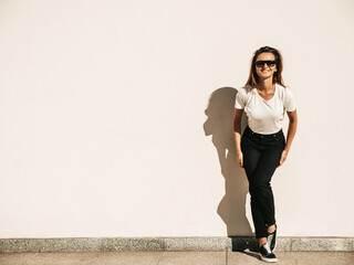 Portrait of beautiful model in sunglasses. Female dressed in summer white T-shirt and jeans. Trendy...