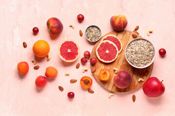 Wooden board with different healthy products on pink background