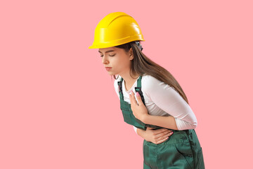 Female builder having heart attack on pink background