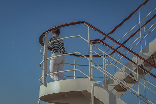 Fototapeta Woman day dreaming on luxurious transatlantic crossing aboard the luxury ocean liner cruise ship Queen Mary with views of the ocean and seascape until horizon with sunset