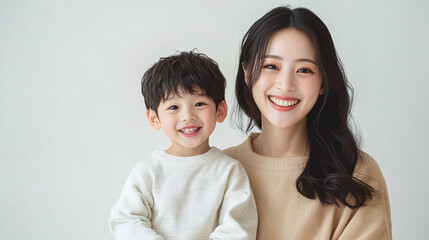 Studio Portrait of a Happy Asian Mother and Daughter: A Family Concept Featuring a Japanese Young Mother and Her Cute Son Interacting and Smiling in Front of a Plain White Background