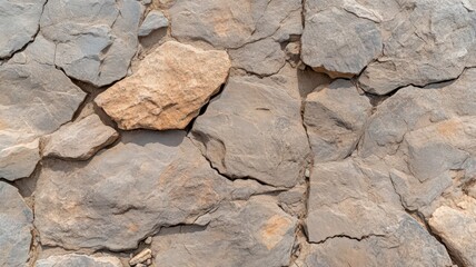 Fototapeta premium Weathered Stone Wall Texture: Gray and Beige Rock Surface with Cracks