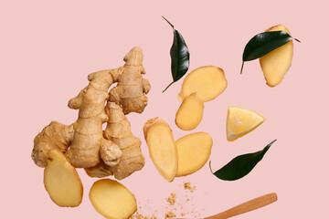 Flying slices of fresh ginger root and leaves on pink background