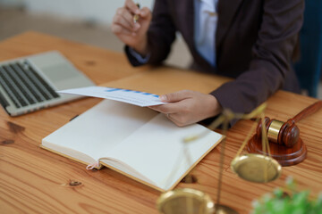 female attorney advisor at a law firm reviews legal documents at her desk equipped with a laptop...