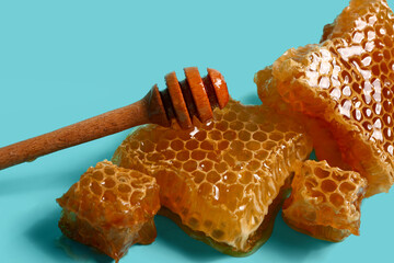 Sweet honeycombs and dipper on blue background
