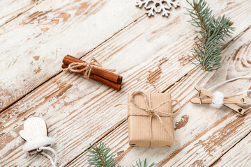 Christmas tree branches with decorations and gift box on white wooden background