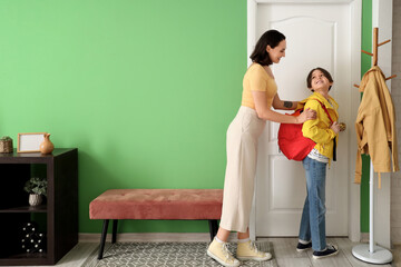 Mother getting her little son ready for school in hallway